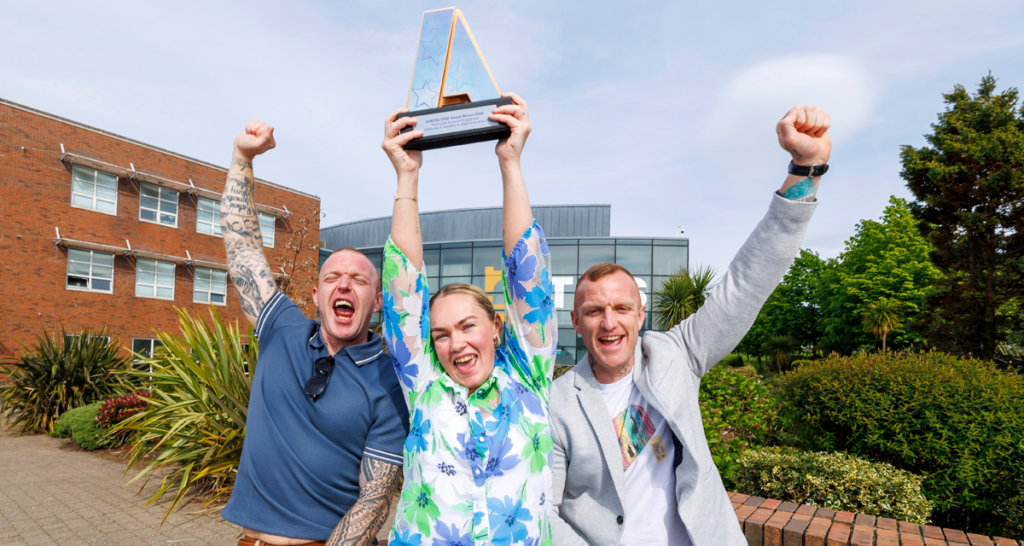 Learners from TUS celebrate outside TUS in Limerick holding up their AONTAS STAR Award, laughing with fists in the air